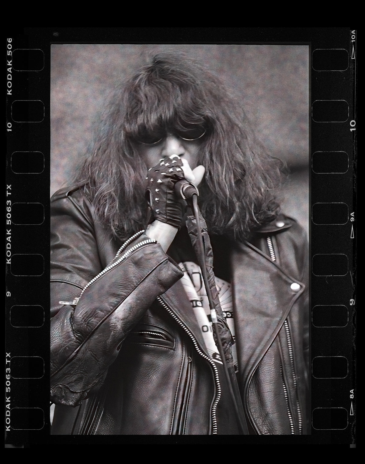 Joey Ramone of The Ramones singing, in black and white with the film rebate showing, Lollapalooza 1996