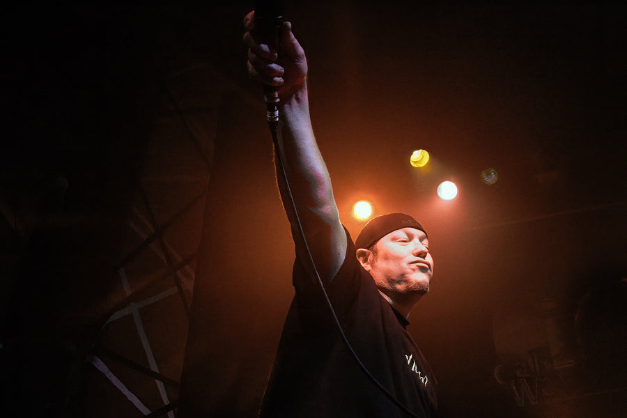Steve Harwell of Smash Mouth with one arm raised, spotlit against black, Cabo Wabo Cantina